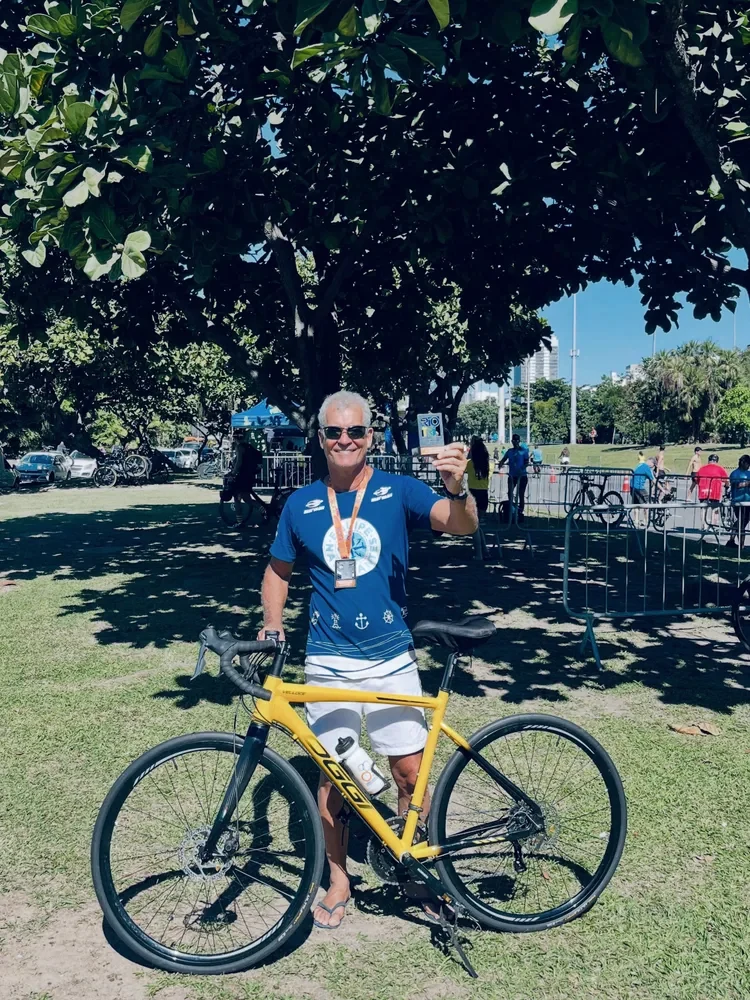 Luiz com medalha e bicicleta após o triathlon.